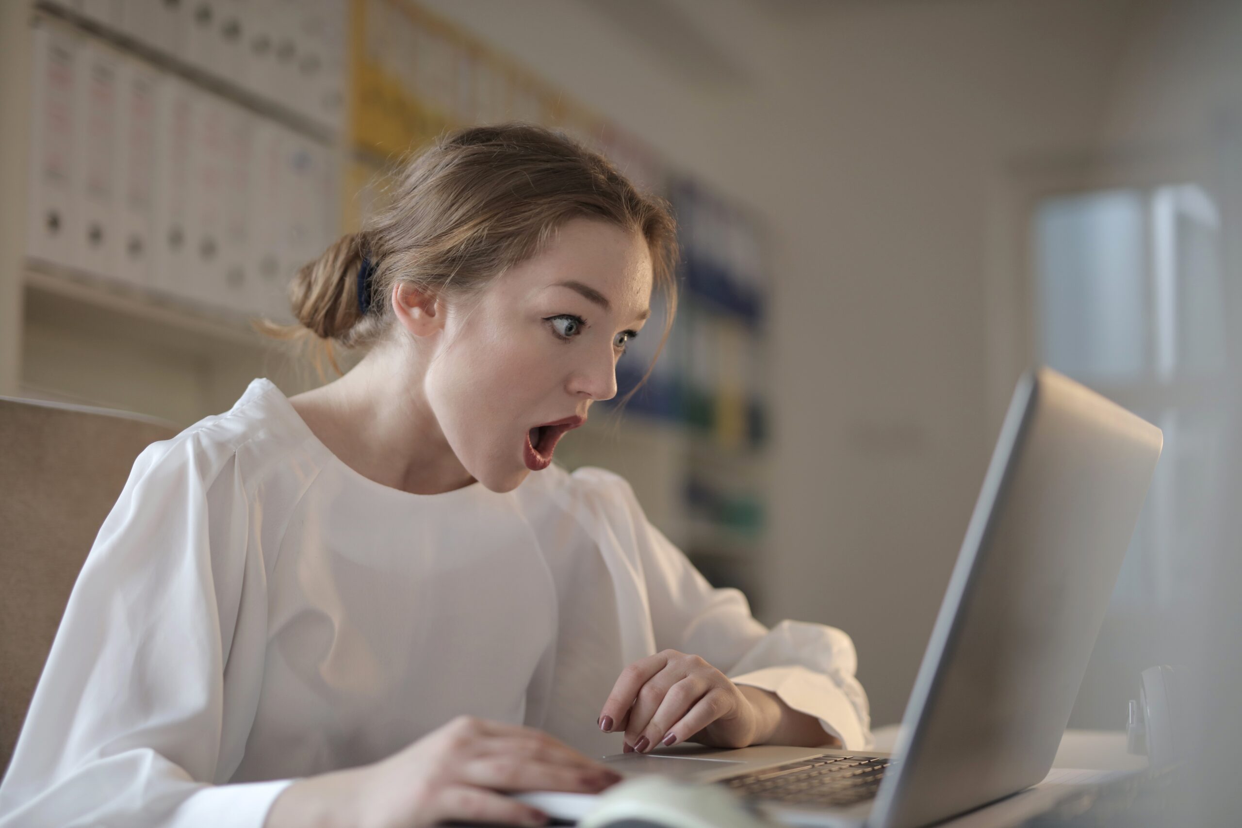 Woman in white long sleeve shirt using silver laptop computer